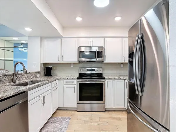 a kitchen with stainless steel appliances granite countertop a stove microwave and cabinets