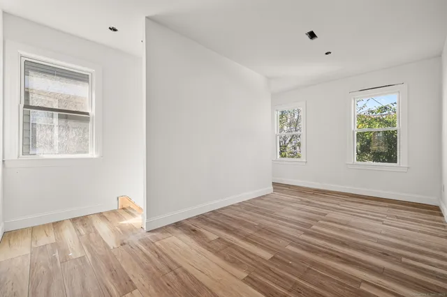 an empty room with wooden floor and windows