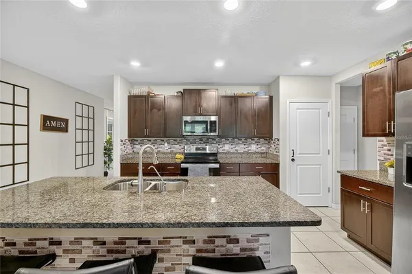 a kitchen with stainless steel appliances a stove a sink a microwave a refrigerator and cabinets
