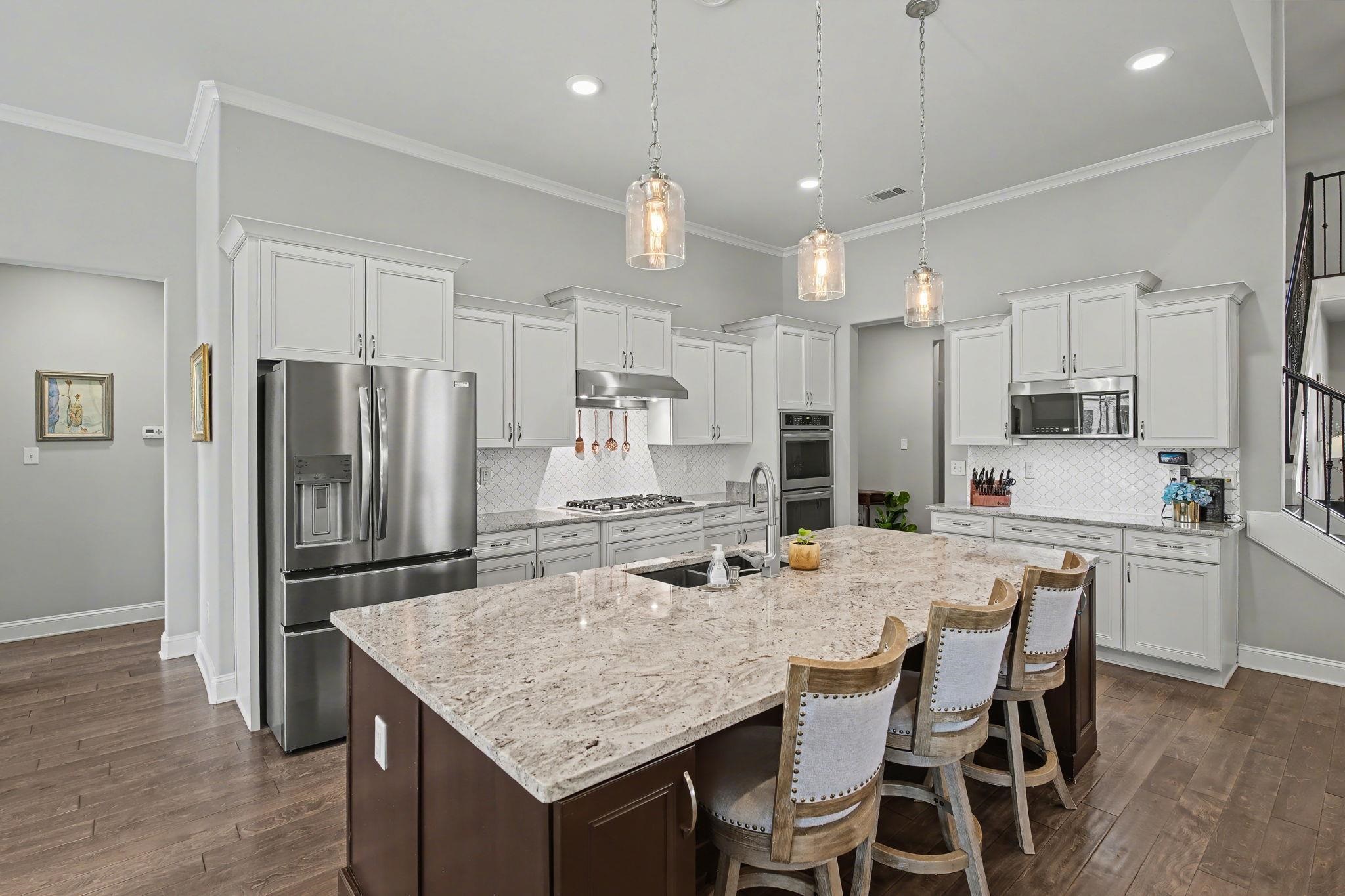 477 Fallen Timbers Cove Collierville, TN 38017 - Photo 12 of 40 a kitchen with stainless steel appliances granite countertop a kitchen island and chairs in it
