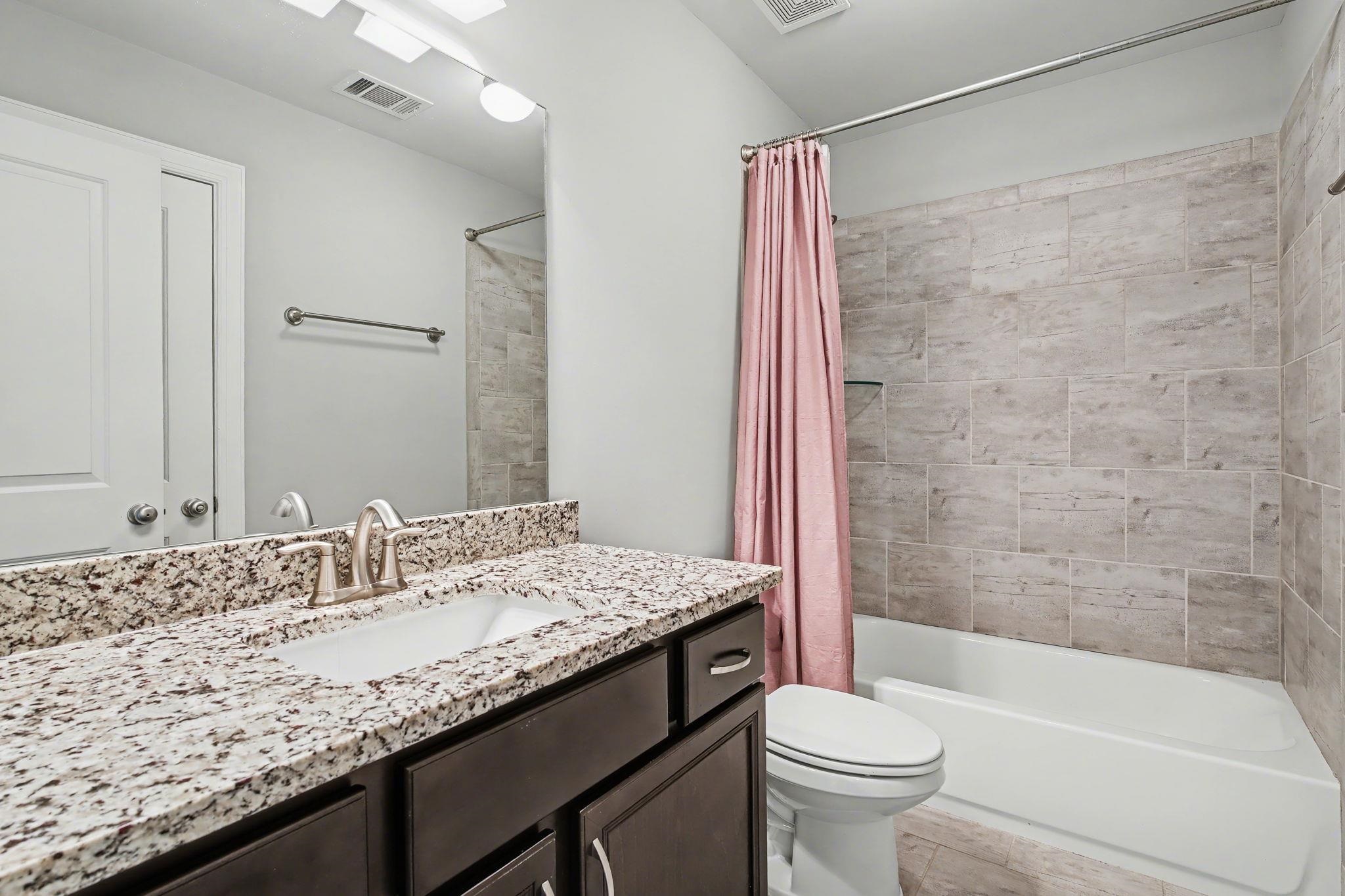 477 Fallen Timbers Cove Collierville, TN 38017 - Photo 29 of 40 a bathroom with a granite countertop sink a toilet a mirror a bathtub and shower