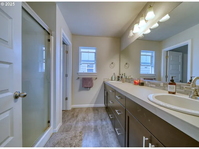 a spacious bathroom with a double vanity sink a mirror and a shower