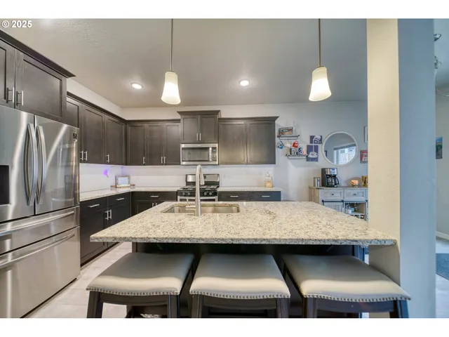 a kitchen with kitchen island granite countertop a refrigerator a sink and wooden cabinets