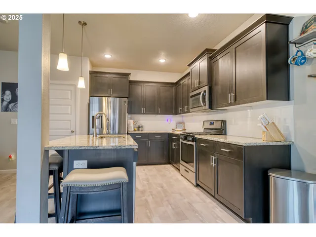 a kitchen with stainless steel appliances granite countertop a sink a stove and a refrigerator