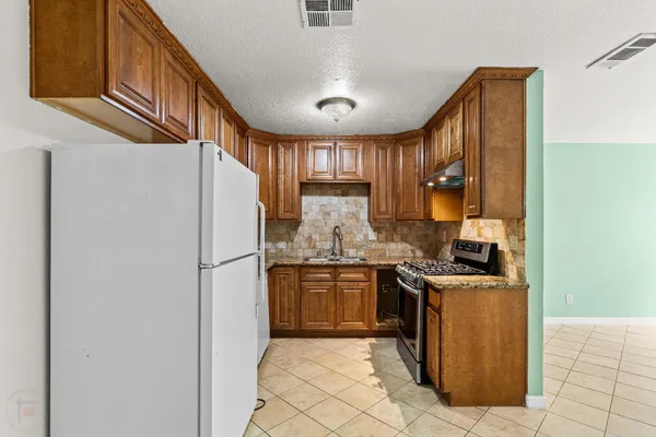 a kitchen with stainless steel appliances granite countertop a refrigerator a sink dishwasher a stove with wooden cabinets