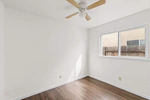 an empty room with a window and a ceiling fan