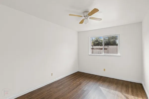 an empty room with wooden floor and ceiling fan
