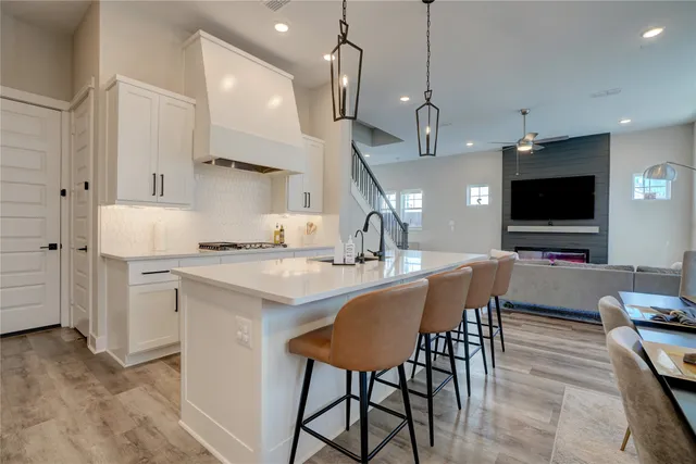 a kitchen with stainless steel appliances a dining table chairs refrigerator and sink