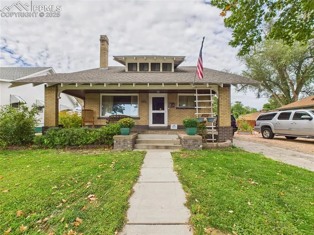a front view of a house with a garden and trees