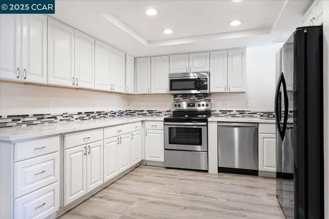 a kitchen with granite countertop white cabinets and stainless steel appliances