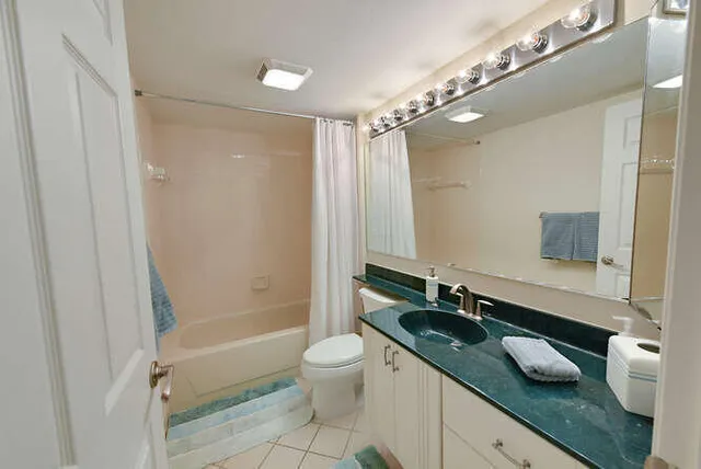 a bathroom with a granite countertop sink a toilet a mirror and shower