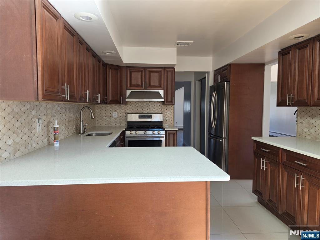 320-322 Williams, Unit 322 Hasbrouck Heights, NJ 07604 - Photo 5 of 12 a kitchen with stainless steel appliances a refrigerator sink and wooden cabinets