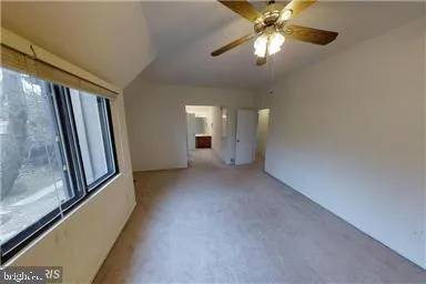 an empty room with windows and fan