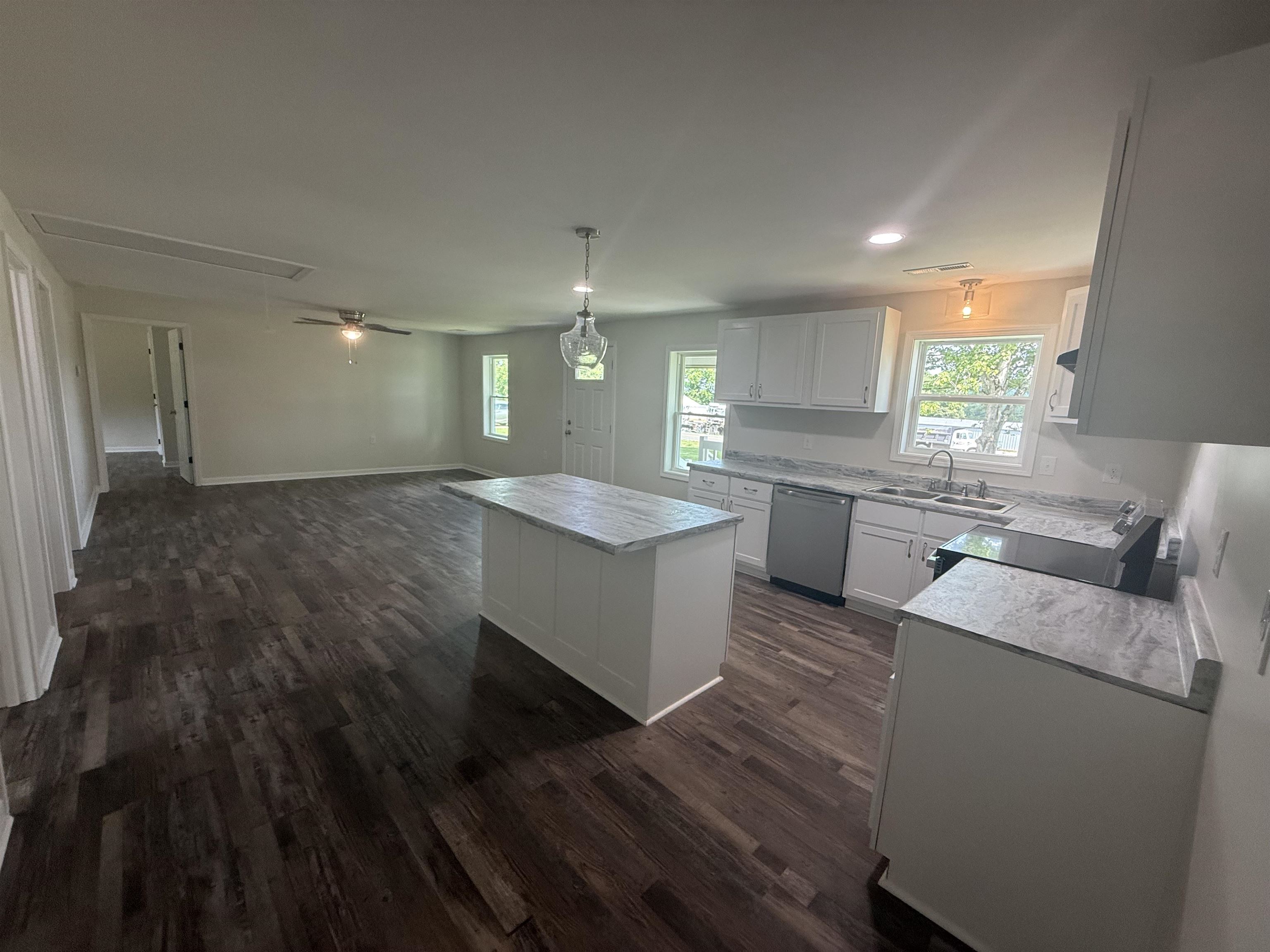 170 Leapwood Road Enville, TN 38332 - Photo 11 of 33 Open-concept living space featuring wood-finish flooring, a kitchen island with stone-finish countertop, white cabinetry, and stainless steel appliances