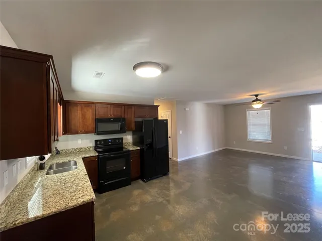 a kitchen with granite countertop a refrigerator a stove top oven and a sink