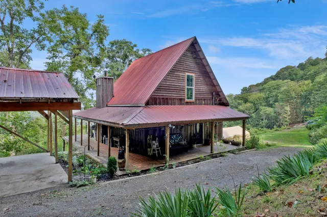 a view of a house with a yard and table and chairs under an umbrella