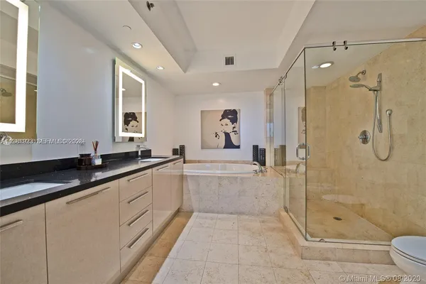 a large bathroom with a granite countertop sink a toilet a mirror and shower