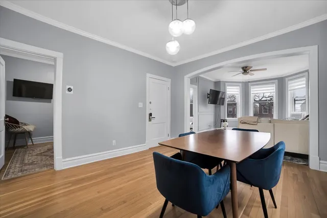a dining room with wooden floor a chandelier a wooden table and chairs
