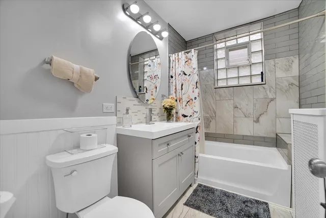 a bathroom with a toilet a sink a mirror a bathtub and shower