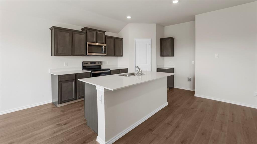 1675 Mantle Road Crandall, TX 75114 - Photo 2 of 27 Kitchen featuring wood-finish flooring, dark wood cabinetry, stainless steel appliances, a center island with an integrated sink, and recessed lighting
