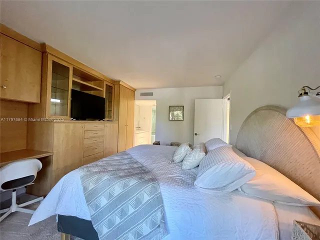 a bedroom with a bed a mirror on dresser and a wooden floor