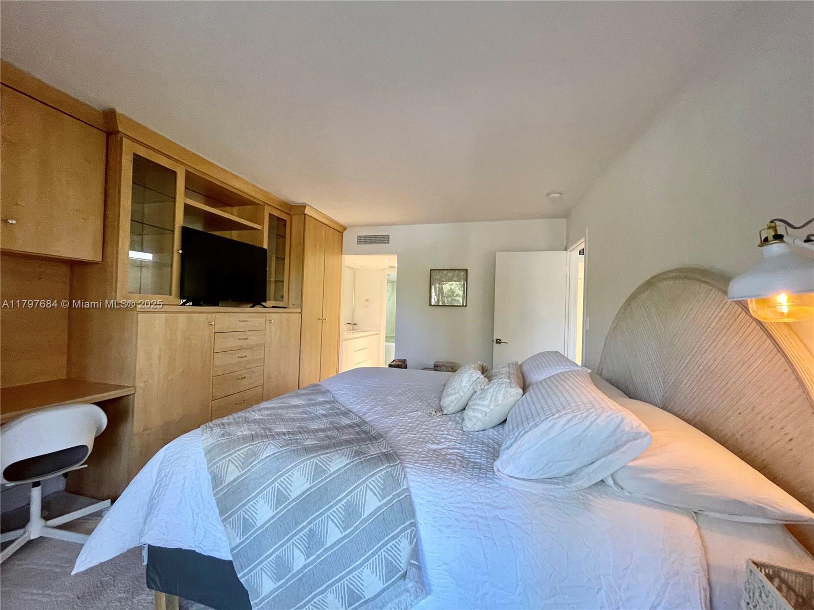 55 Ocean Ln Drive, Unit 2030 Key Biscayne, FL 33149 - Photo 16 of 19 a bedroom with a bed a mirror on dresser and a wooden floor