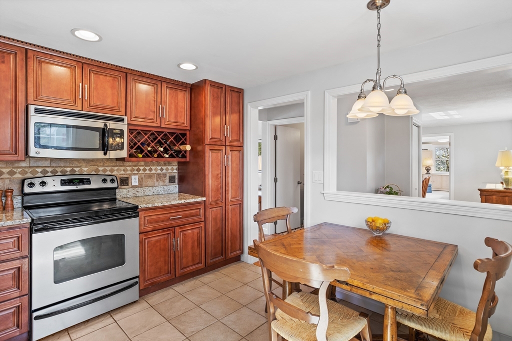 66 Old Stow Road Concord, MA 01742 - Photo 15 of 42 a kitchen with stainless steel appliances granite countertop a stove a sink dishwasher a microwave oven with a dining table and chairs
