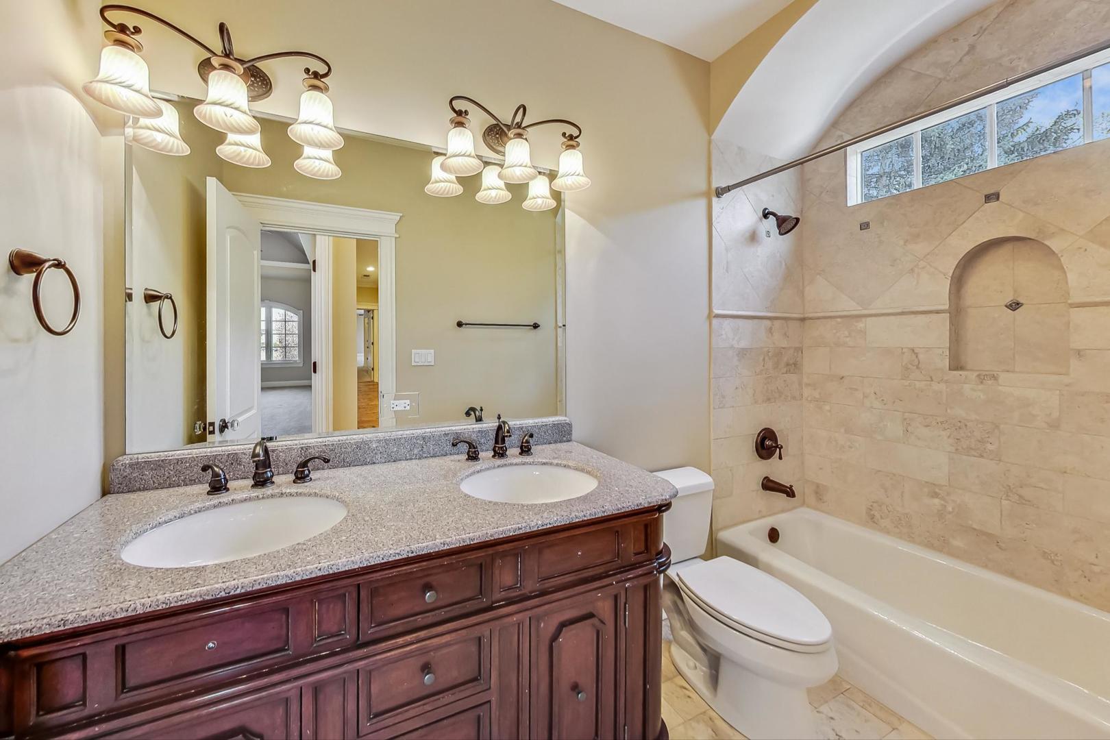 136 Fuller Road Hinsdale, IL 60521 - Photo 31 of 53 a bathroom with a granite countertop sink a toilet a mirror a bathtub and shower