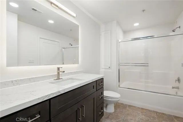 a bathroom with a granite countertop sink toilet a large mirror a shower and vanity