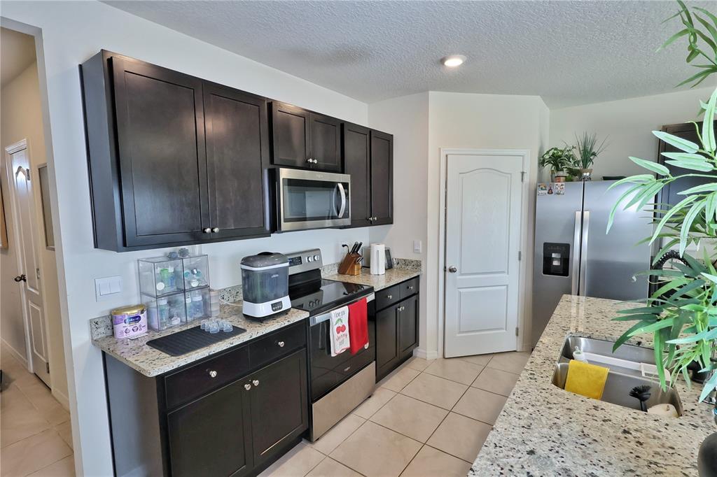 1724 Buckeye Road Davenport, FL 33837 - Photo 19 of 53 a kitchen with stainless steel appliances granite countertop a refrigerator and a sink