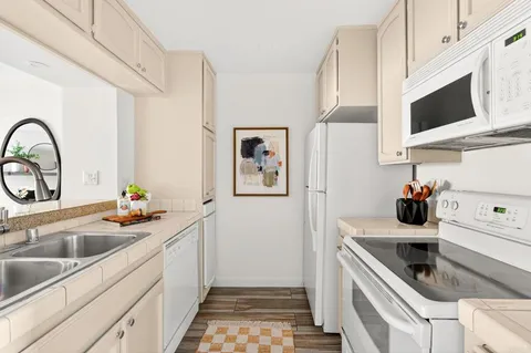 a kitchen with stainless steel appliances a sink a microwave a refrigerator and cabinets