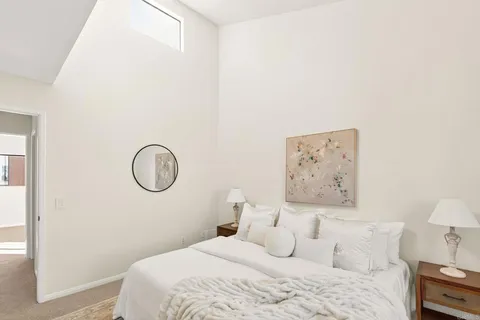 a bedroom with a bed and a lamp on the wall