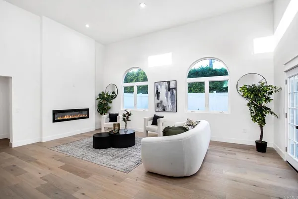 a living room with furniture kitchen view and a wooden floor