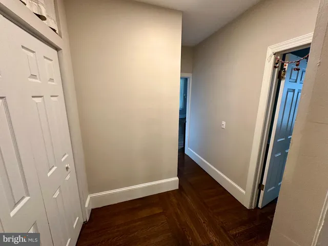 an empty room with wooden floor and a hallway