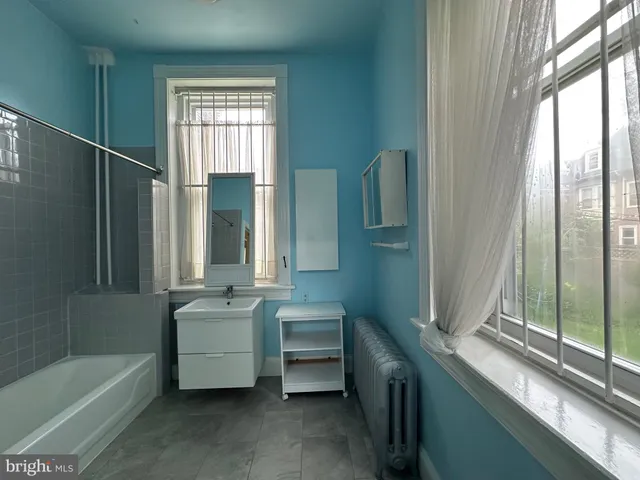 a bathroom with a tub a sink and a window
