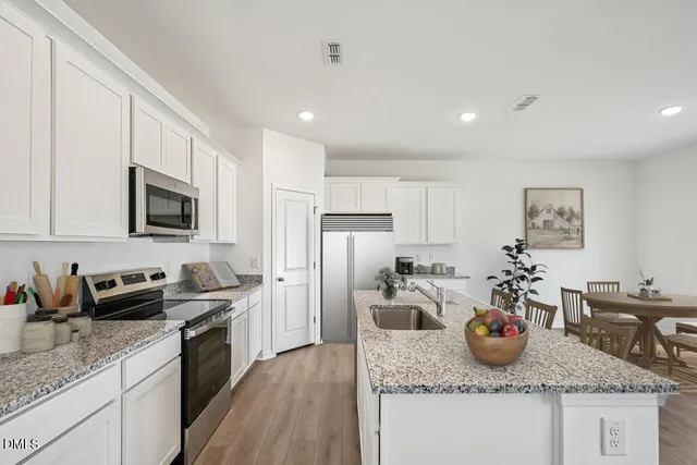 a kitchen with stainless steel appliances kitchen island granite countertop a refrigerator and a stove top oven