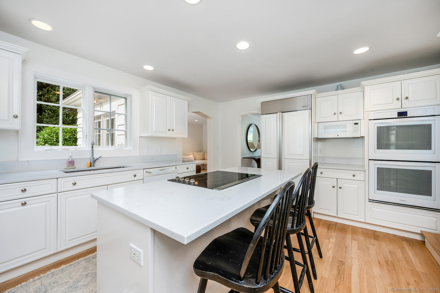 128 5 Mile River Road Darien, CT 06820 - Photo 6 of 23 a kitchen with a stove a sink a kitchen island with a dining table and chairs