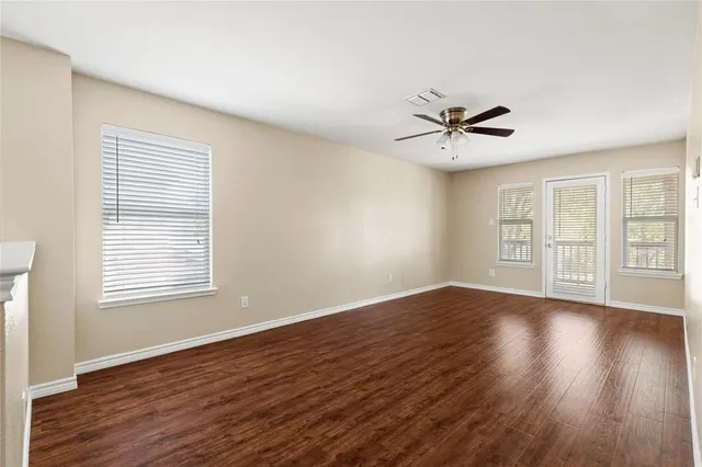 a view of an empty room with wooden floor and a window