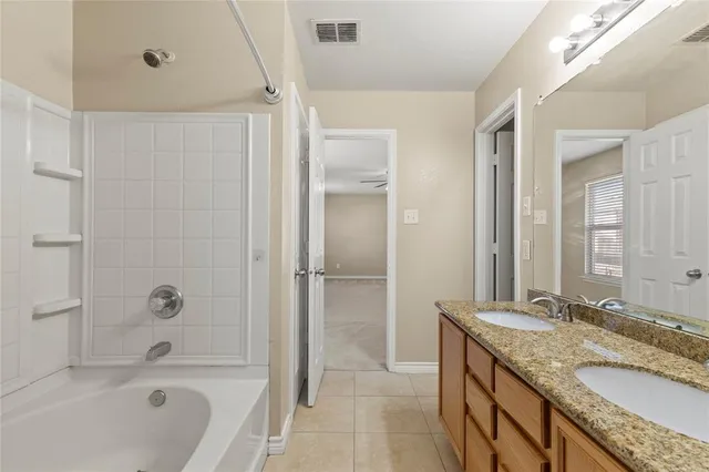 a bathroom with a granite countertop bathtub shower sink and mirror