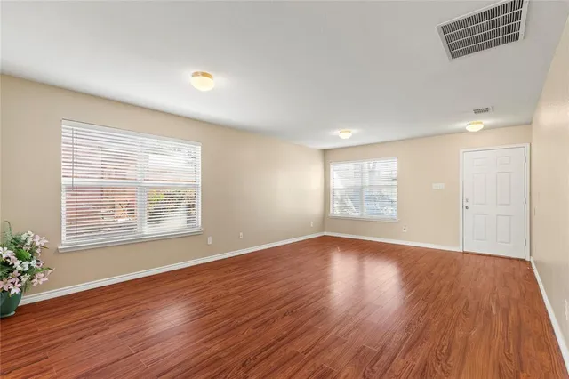a view of an empty room with wooden floor and a window