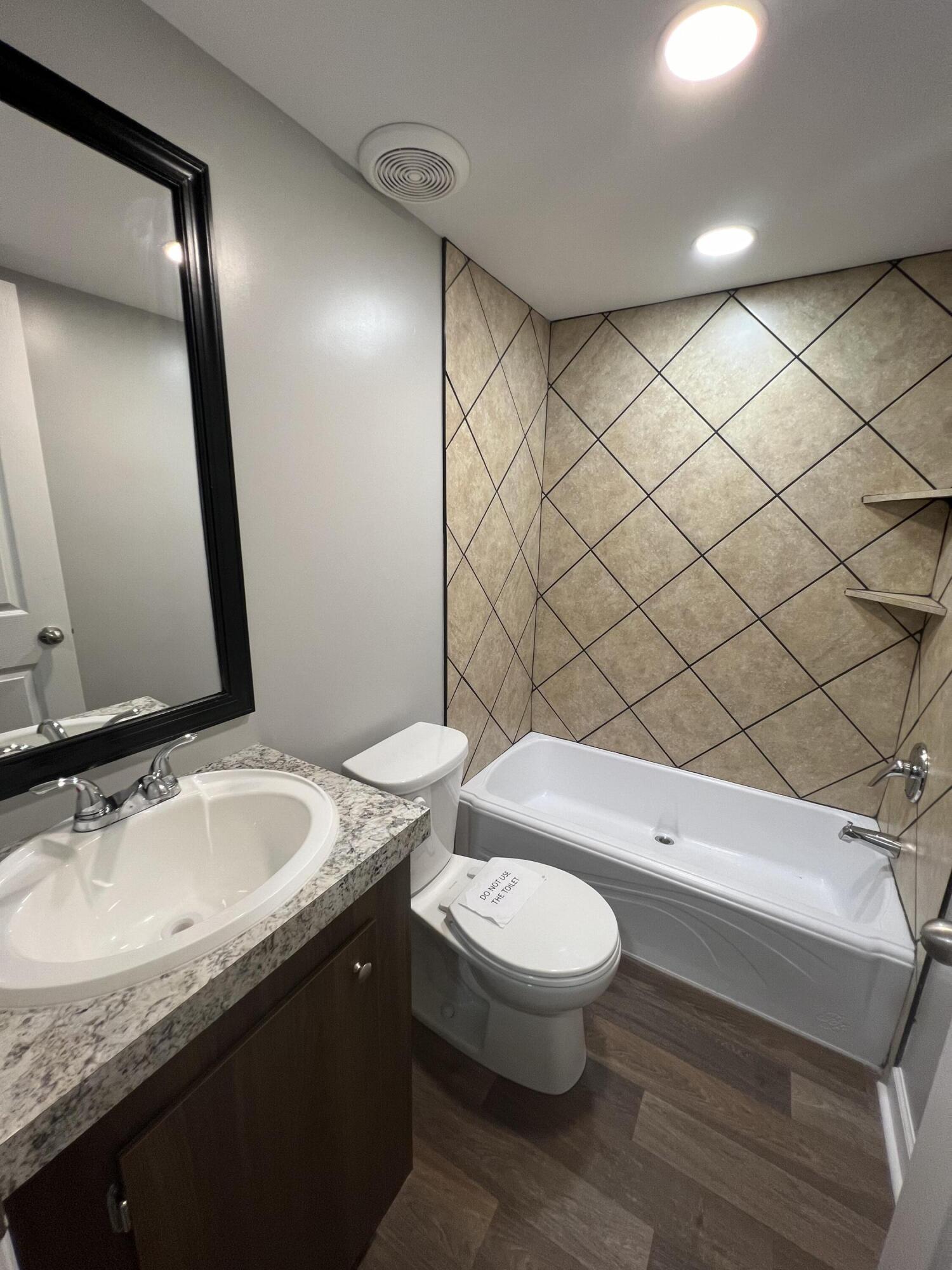 203 Byrnes Street Goodview, VA 24095 - Photo 12 of 13 a bathroom with a granite countertop bathtub sink vanity mirror and toilet