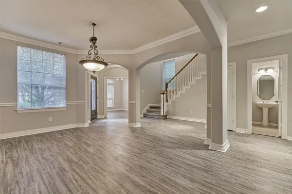 a view of a room with wooden floor ceiling fan and windows