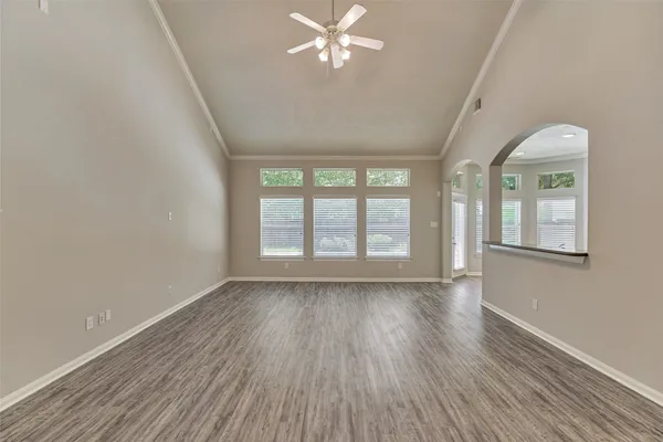 an empty room with wooden floor fan and windows