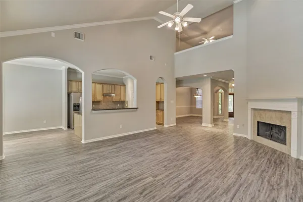 a view of a livingroom with wooden floor a ceiling fan and staircase