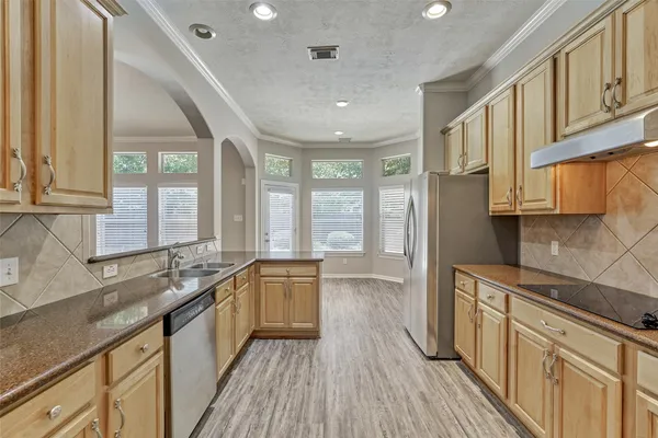 a large kitchen with stainless steel appliances granite countertop a lot of counter space and wooden floors