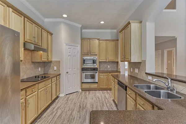 a kitchen with stainless steel appliances granite countertop a refrigerator a stove and a sink with wooden floors