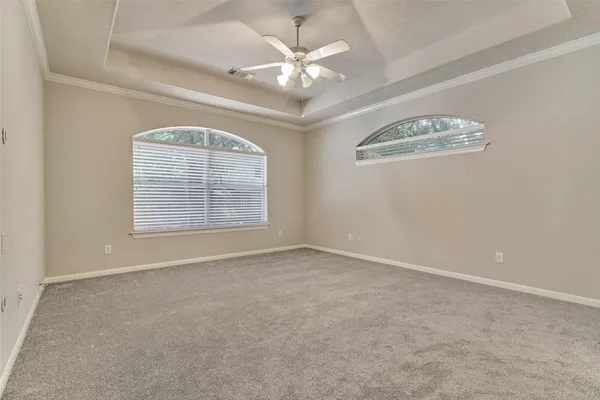 an empty room with windows and chandelier fan