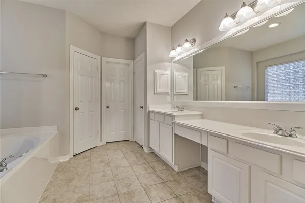 a spacious bathroom with a double vanity sink mirror and bathtub