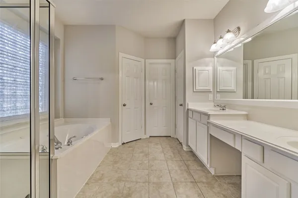 a spacious bathroom with a tub sink shower and mirror
