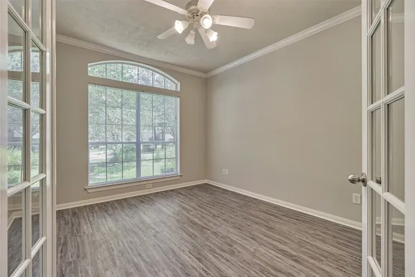 an empty room with wooden floor fan and windows